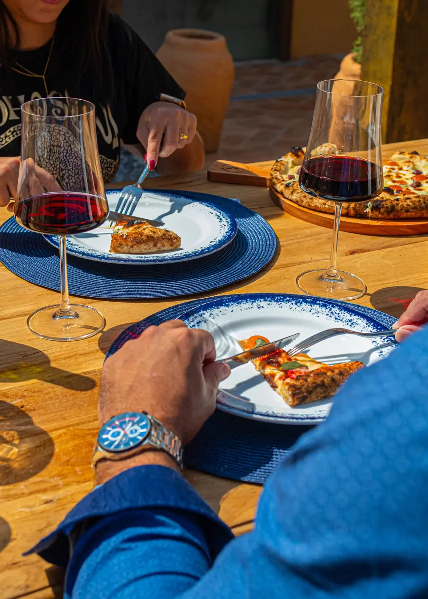 Clientes compartilhando pizzas e vinho na Alleghe